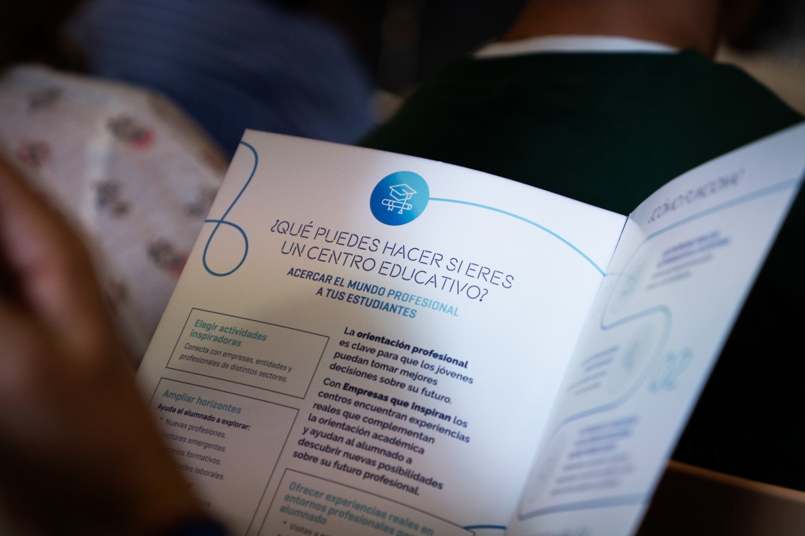 Un folleto abierto sobre orientación profesional para centros educativos, sostenido por una persona sentada.