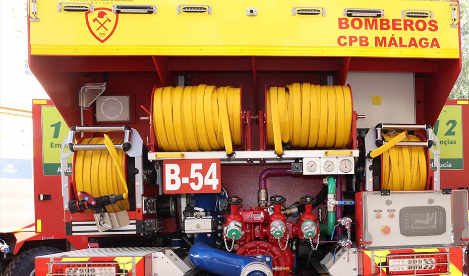 Parte trasera de un camión de bomberos rojo con mangueras amarillas enrolladas, bombas y el rótulo BOMBEROS CPB MÁLAGA.
