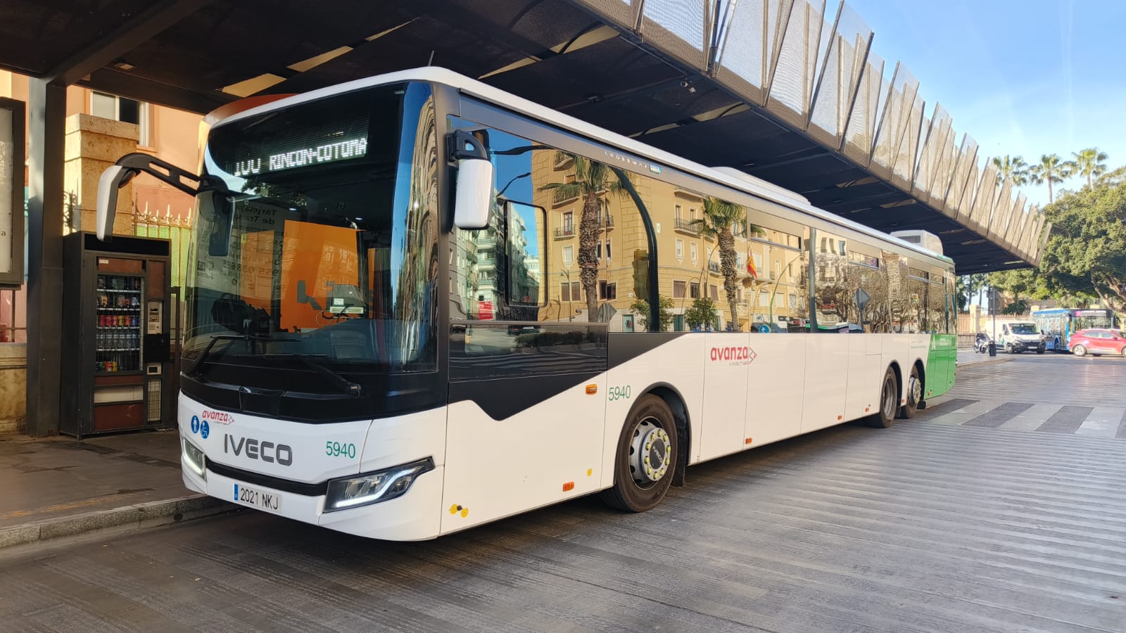 Un autobús blanco de la marca Iveco, con el rótulo Avanza y el número 5940, aparcado bajo una marquesina en una estación.