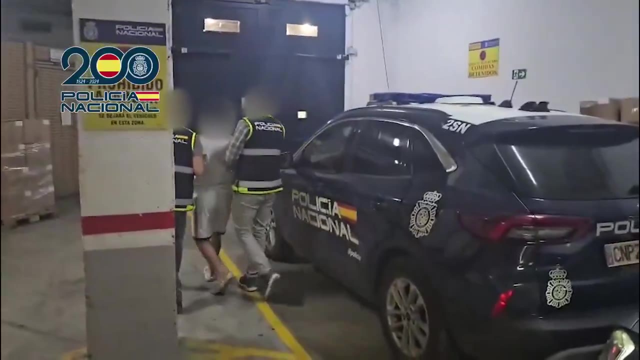 Agentes de la Policía Nacional conducen al detenido, con el rostro difuminado, hacia un coche patrulla en Málaga